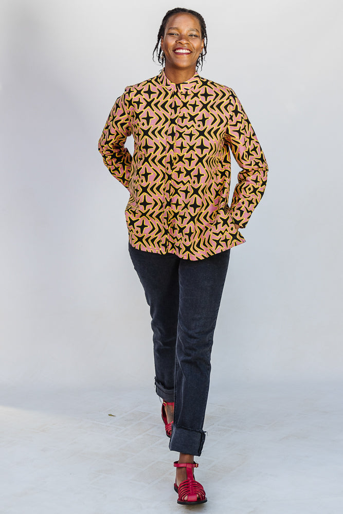 Model wearing beige, yellow and black geometric print shirt.