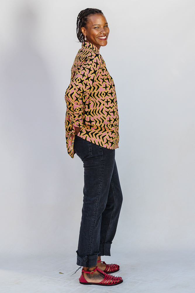 Model wearing beige, yellow and black geometric print shirt.