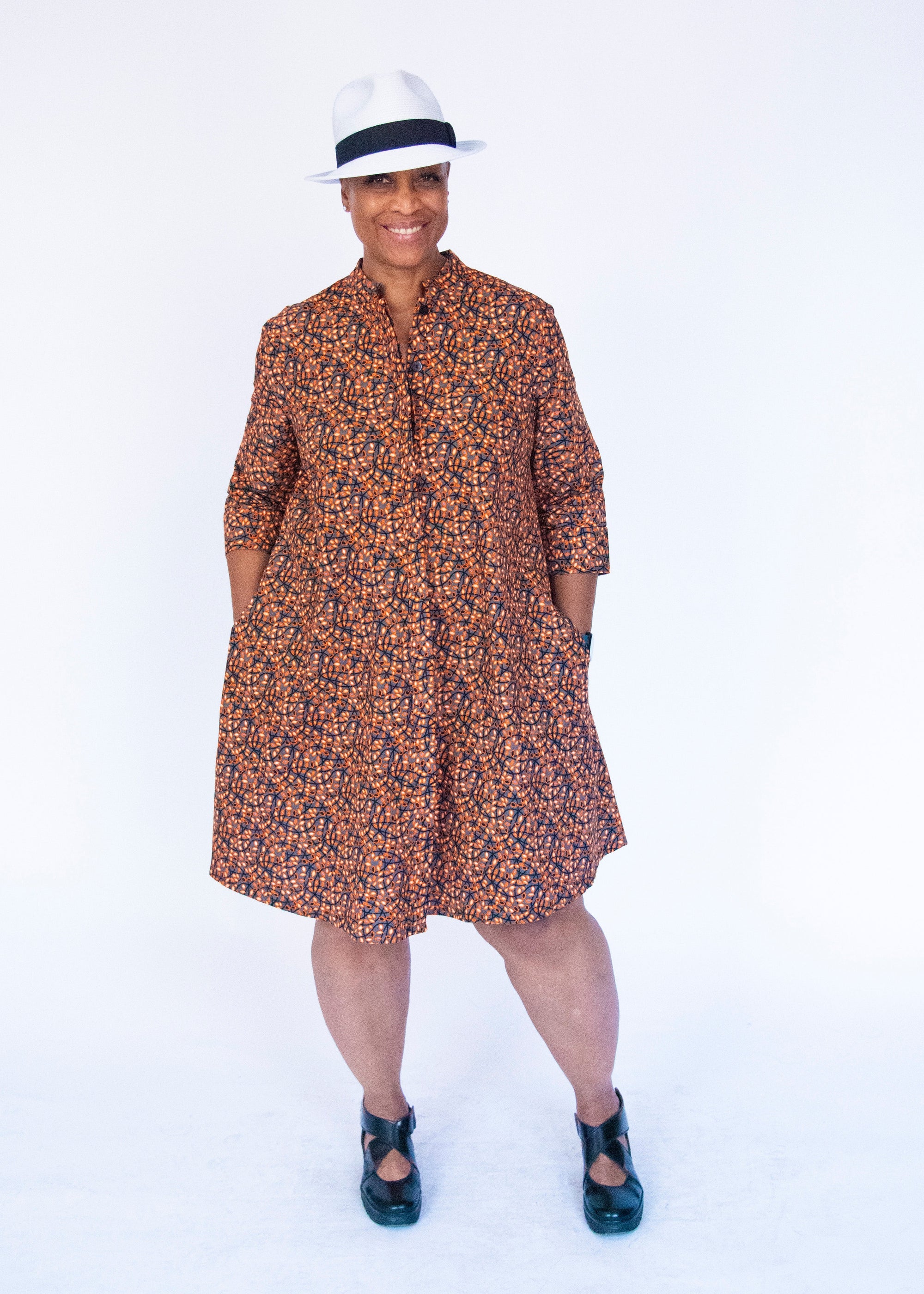 Model wearing grey dress with black and orange vine design.