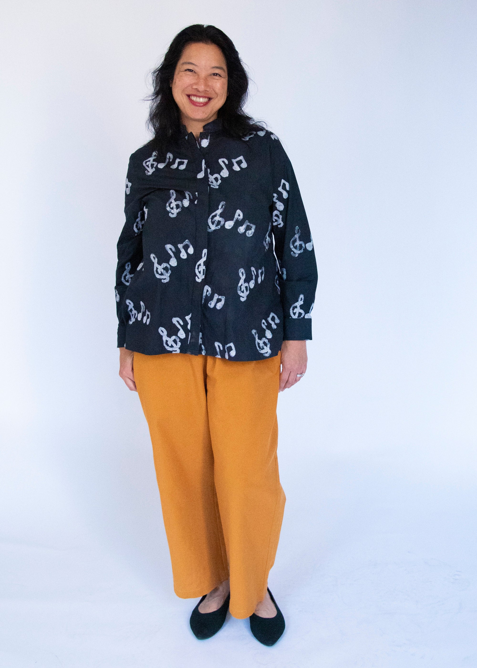 Model wearing black long sleeved shirt with white music print design.