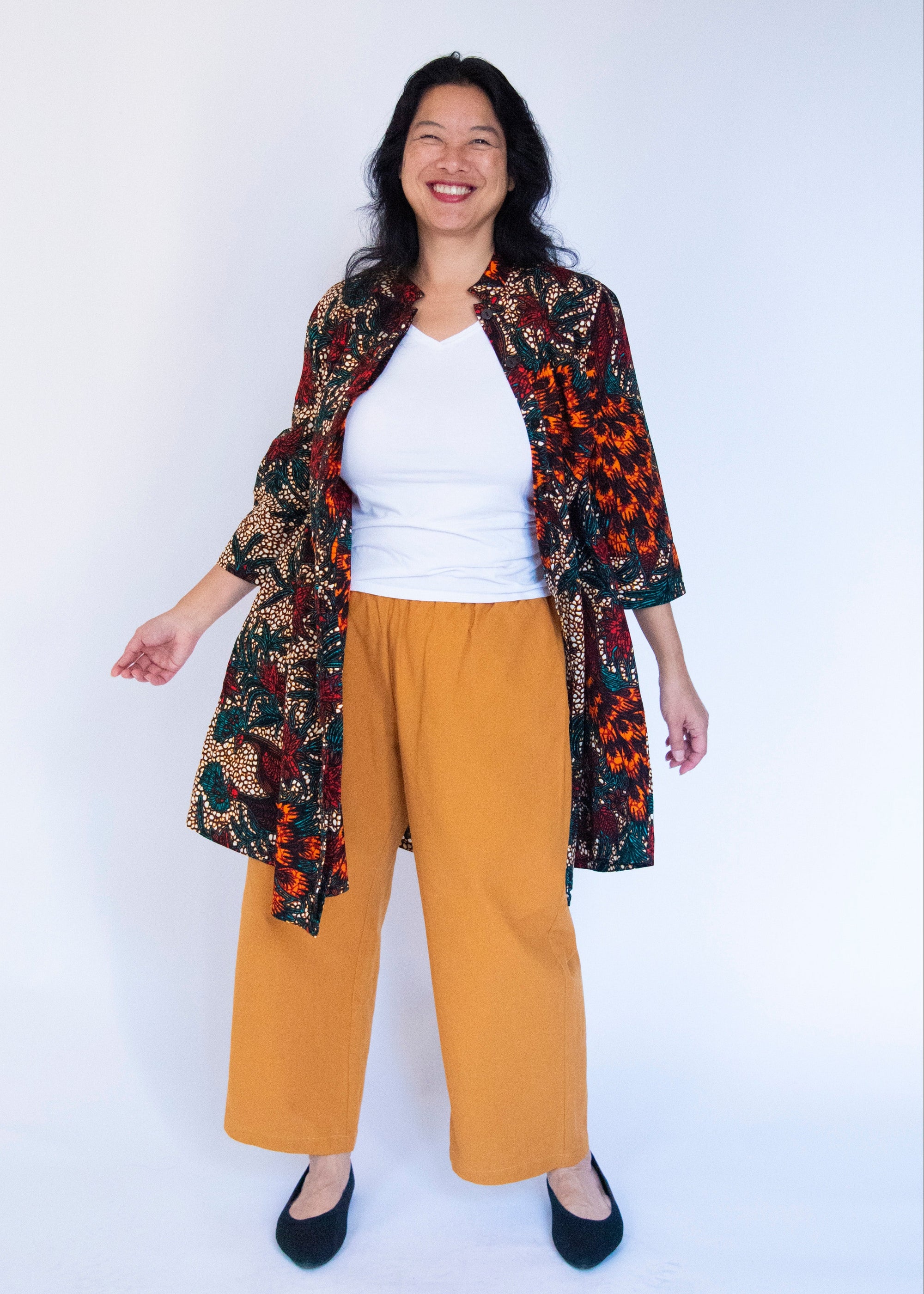 Model wearing orange, brown and green dress.