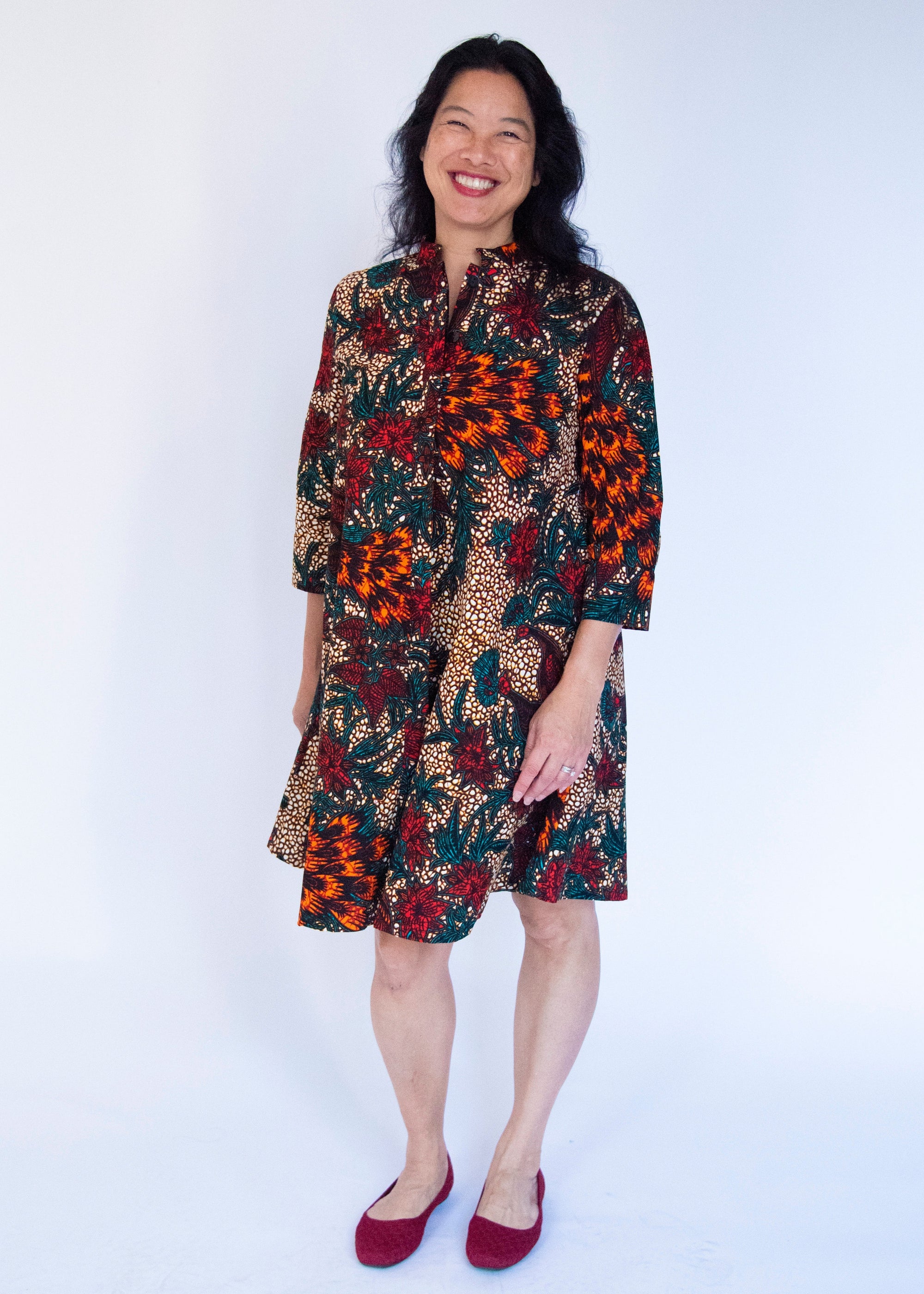 Model wearing orange, brown and green dress.