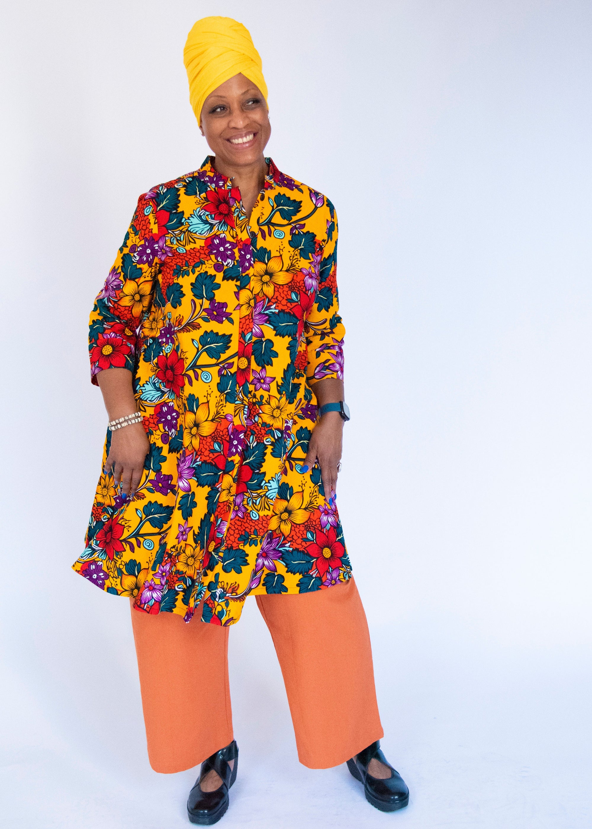 Model wearing yellow dress with multicolor floral print.