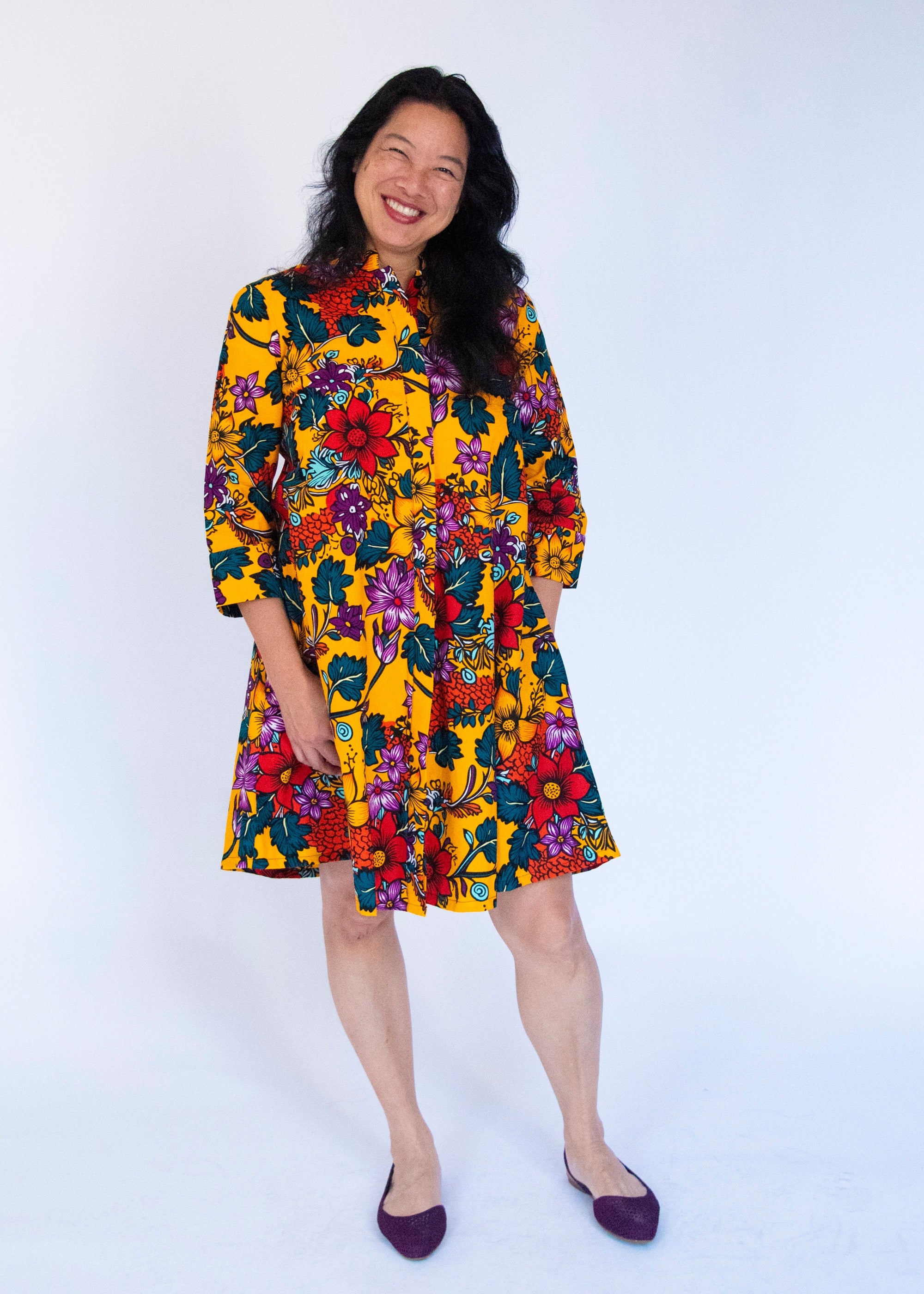 Model wearing yellow dress with multicolor floral print.