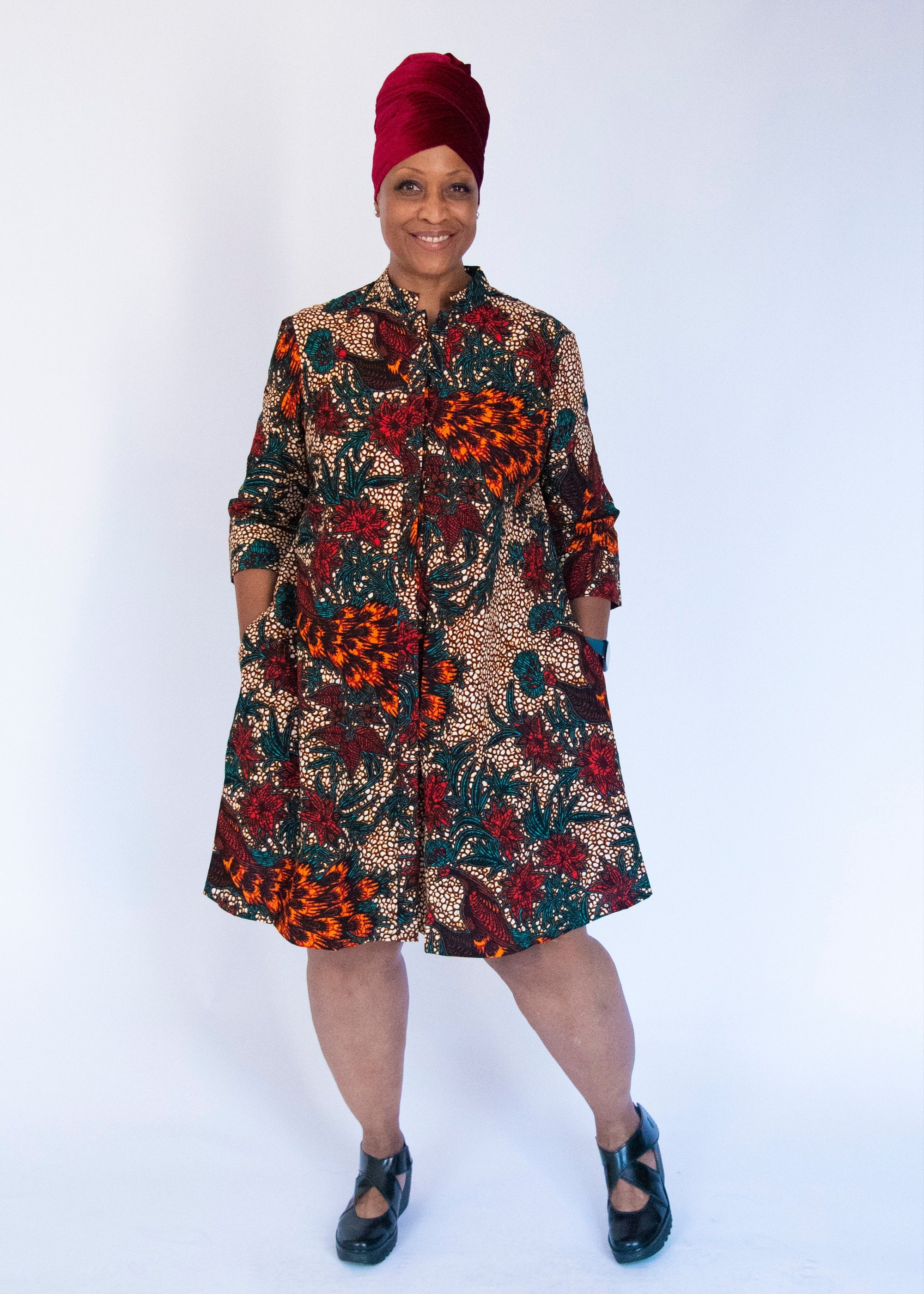 Model wearing orange, brown and green dress.