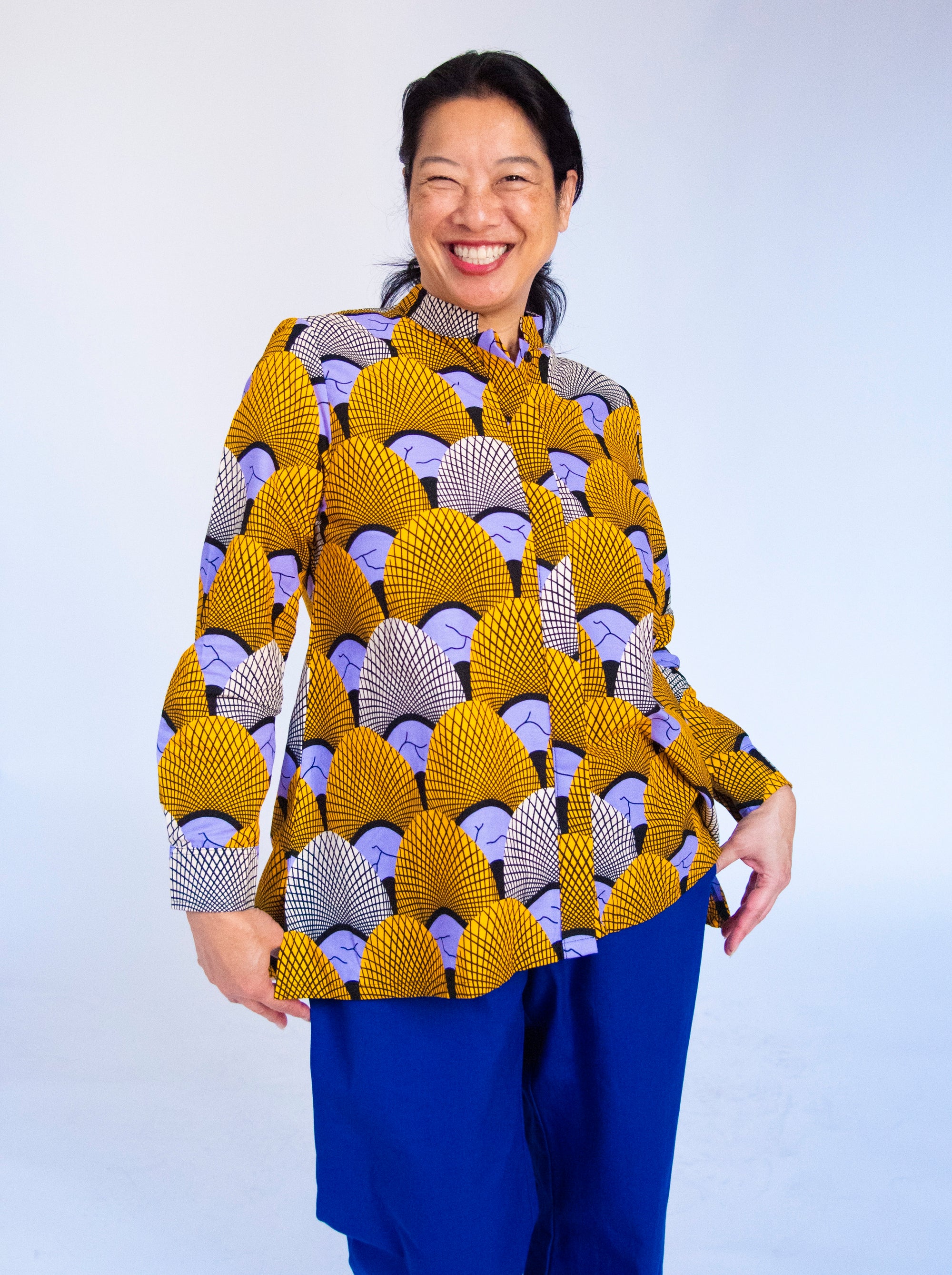 Model wearing long sleeved orange and purple geometric print shirt.