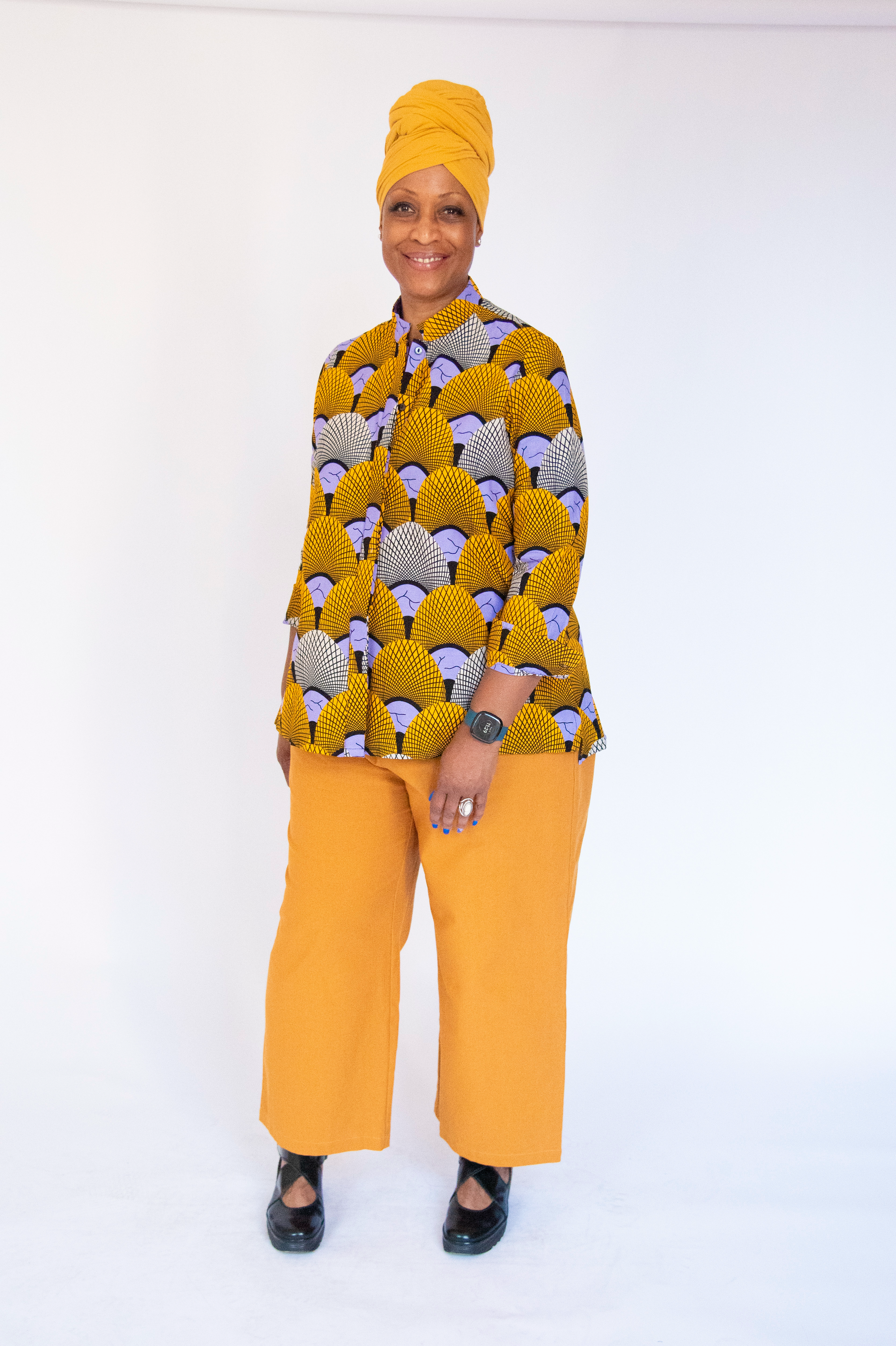 Model wearing long sleeved orange and purple geometric print shirt.