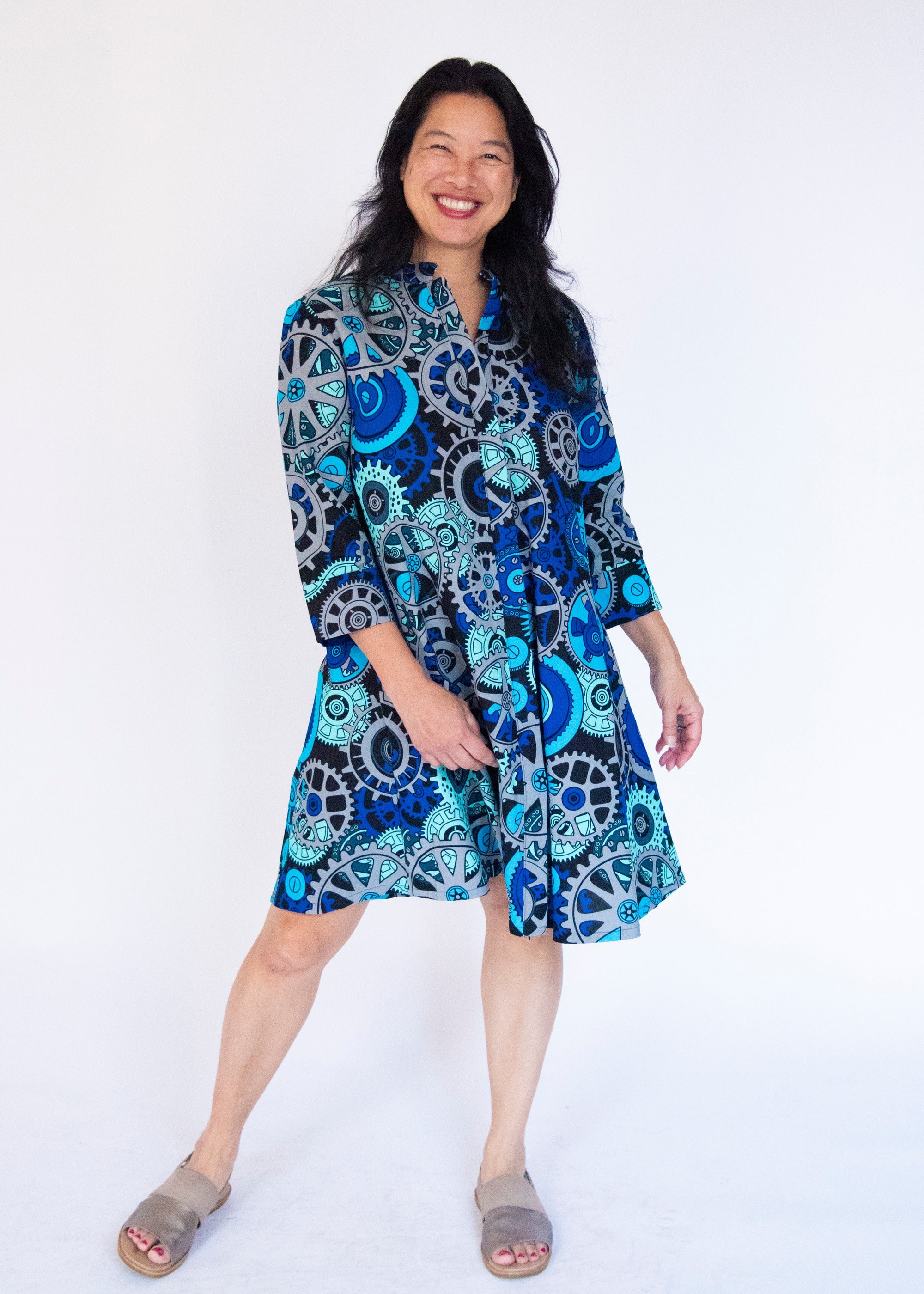 Model wearing dress with blue and grey gear graphic print.