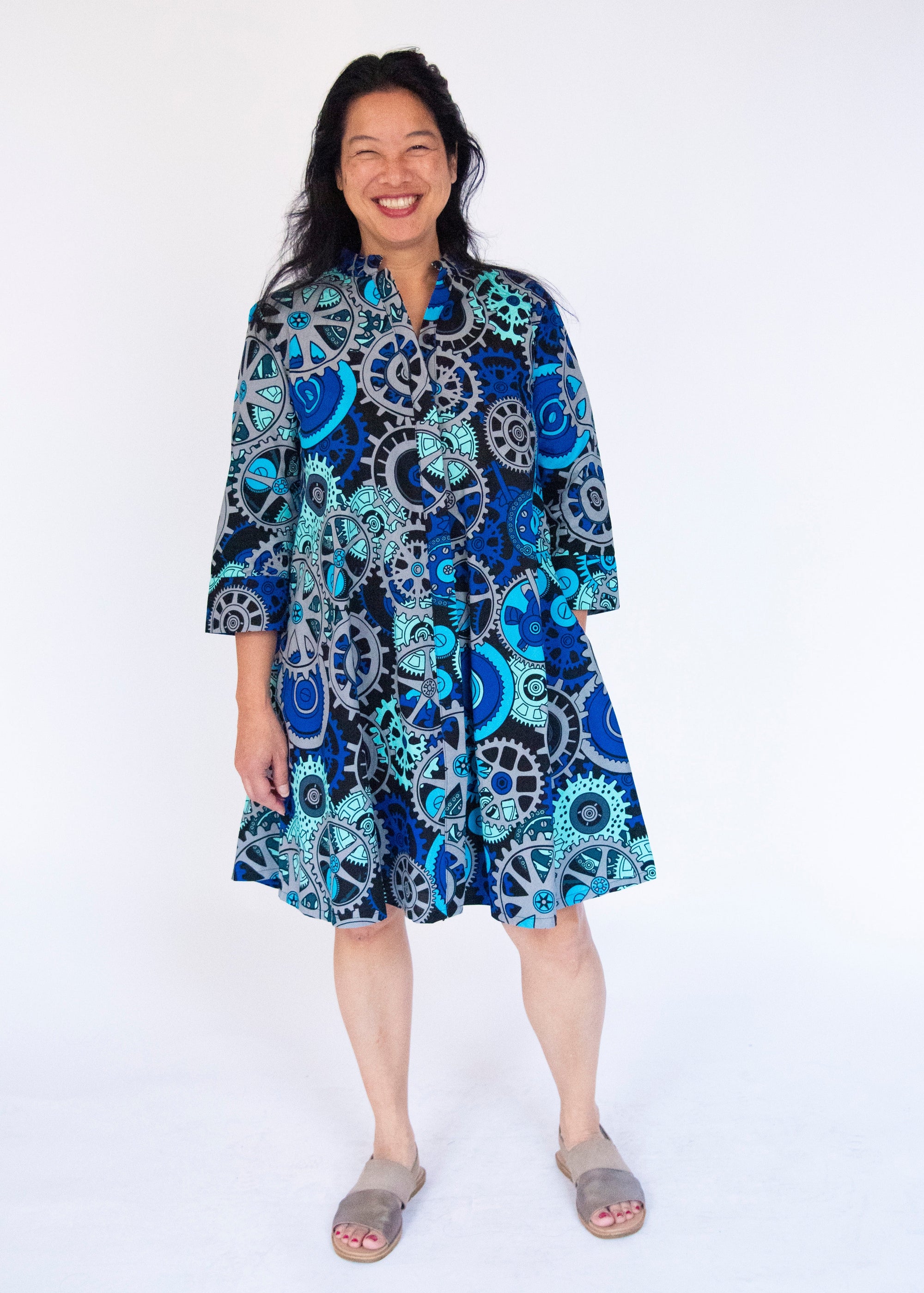 Model wearing dress with blue and grey gear graphic print.