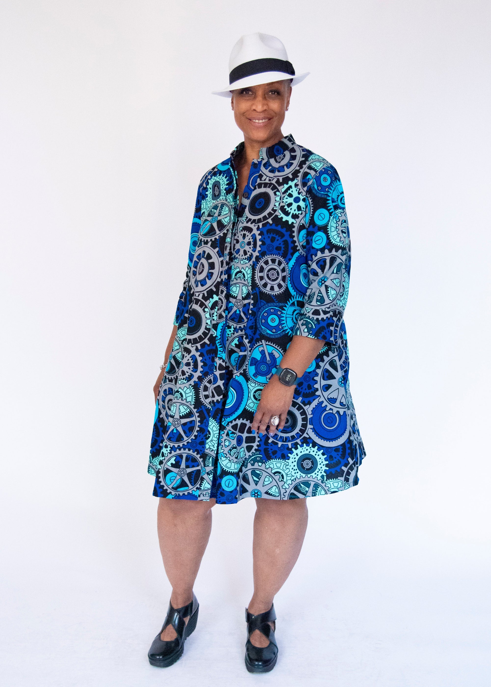 Model wearing dress with blue and grey gear graphic print.