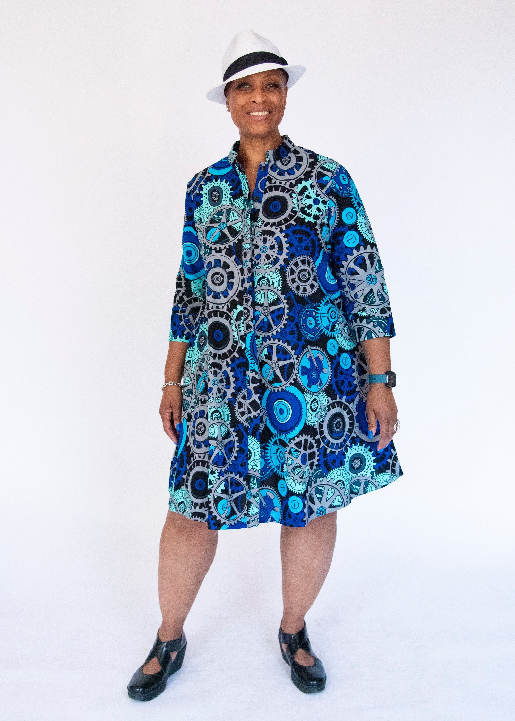 Model wearing dress with blue and grey gear graphic print.