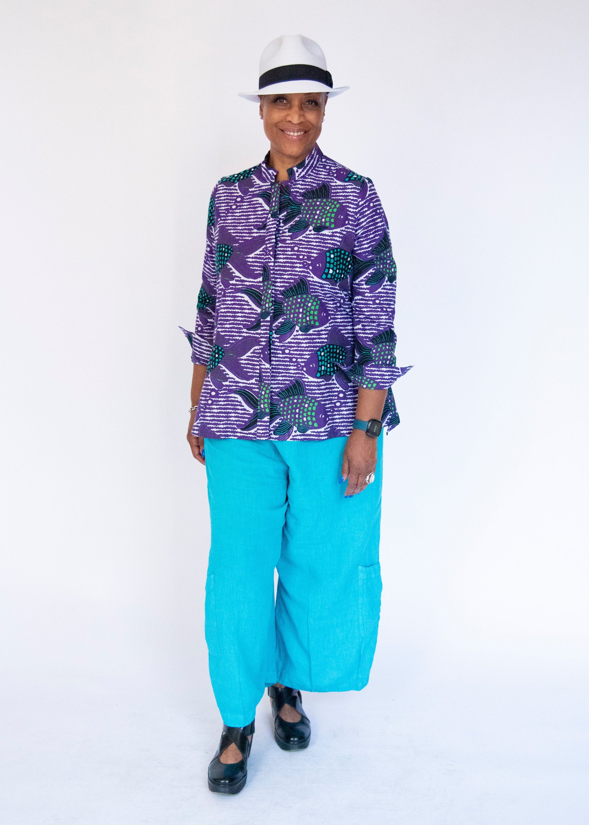 Model wearing long sleeved shirt with purple and green fish print.