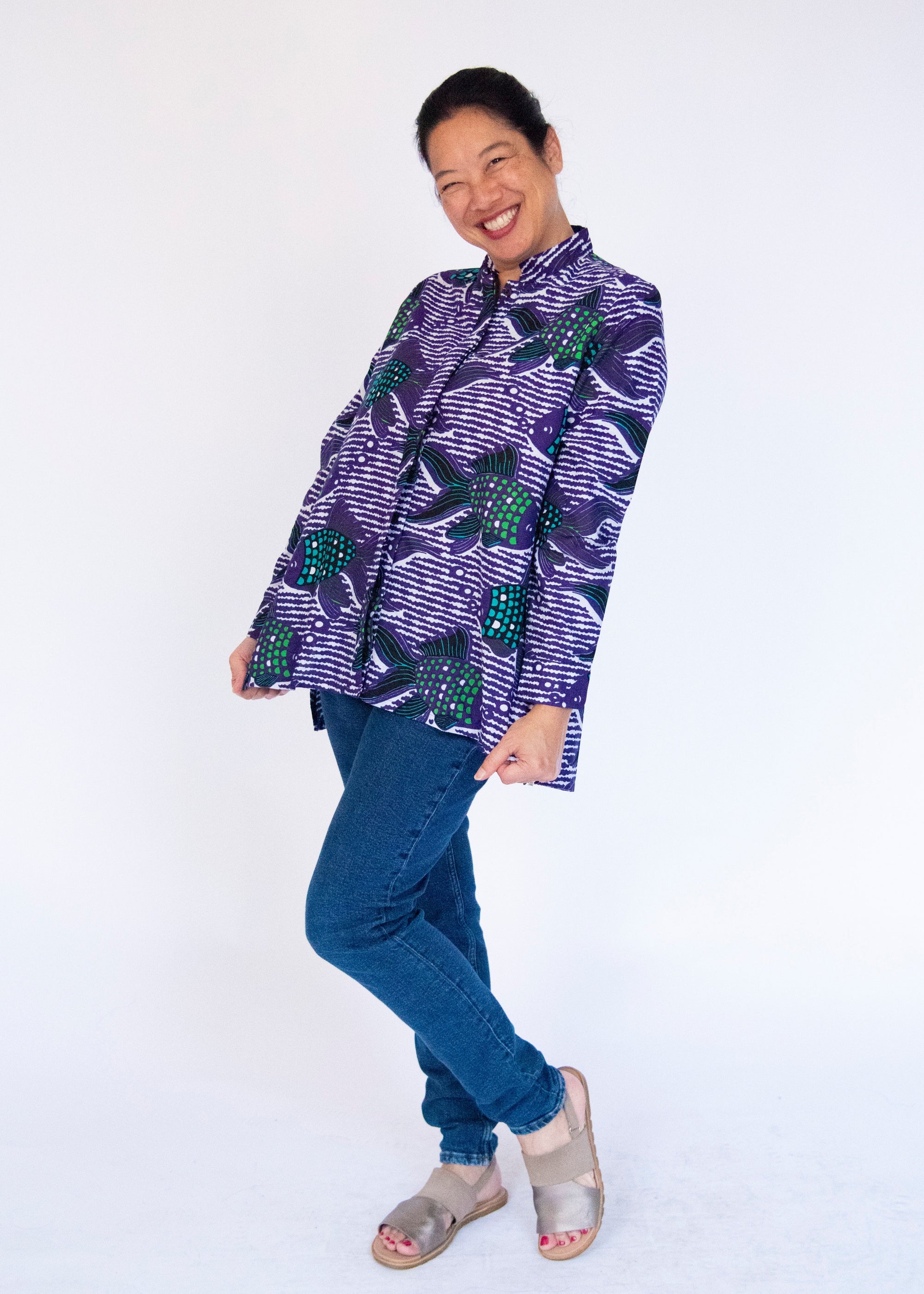 Model wearing long sleeved shirt with purple and green fish print.