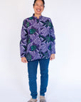 Model wearing long sleeved shirt with purple and green fish print.