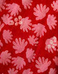 Close up display of red dress with pink flowers, fabric.