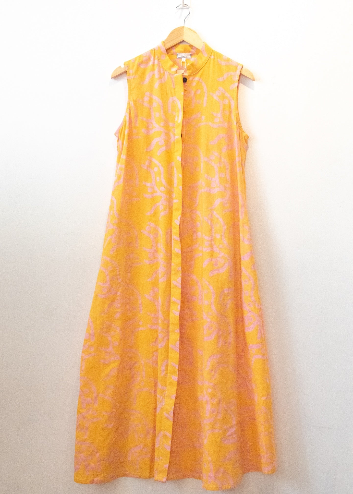Display of yellow sleeveless dress with abstract pink print.