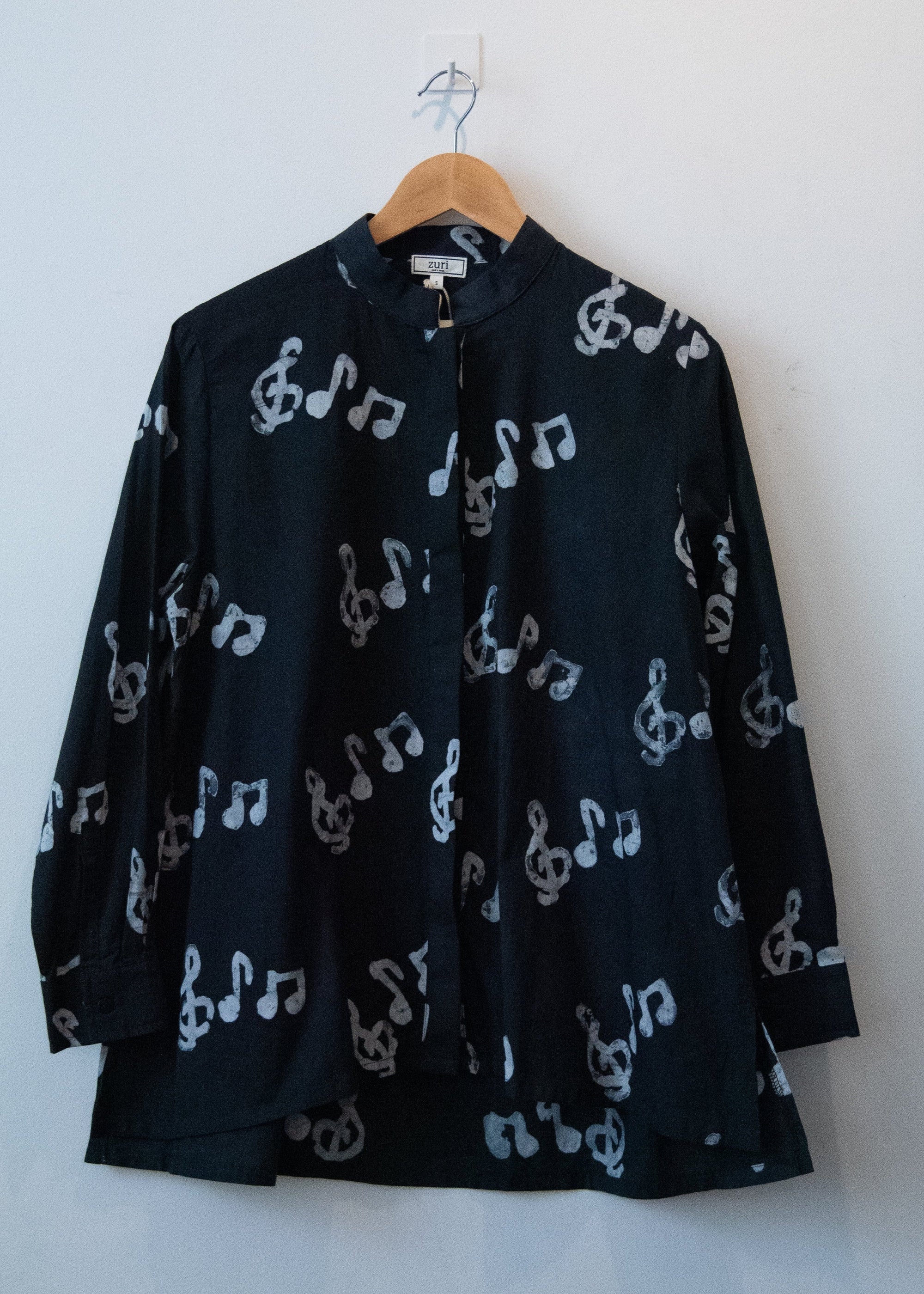 Display of black long sleeved shirt with white music print design.