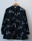 Display of black long sleeved shirt with white music print design.