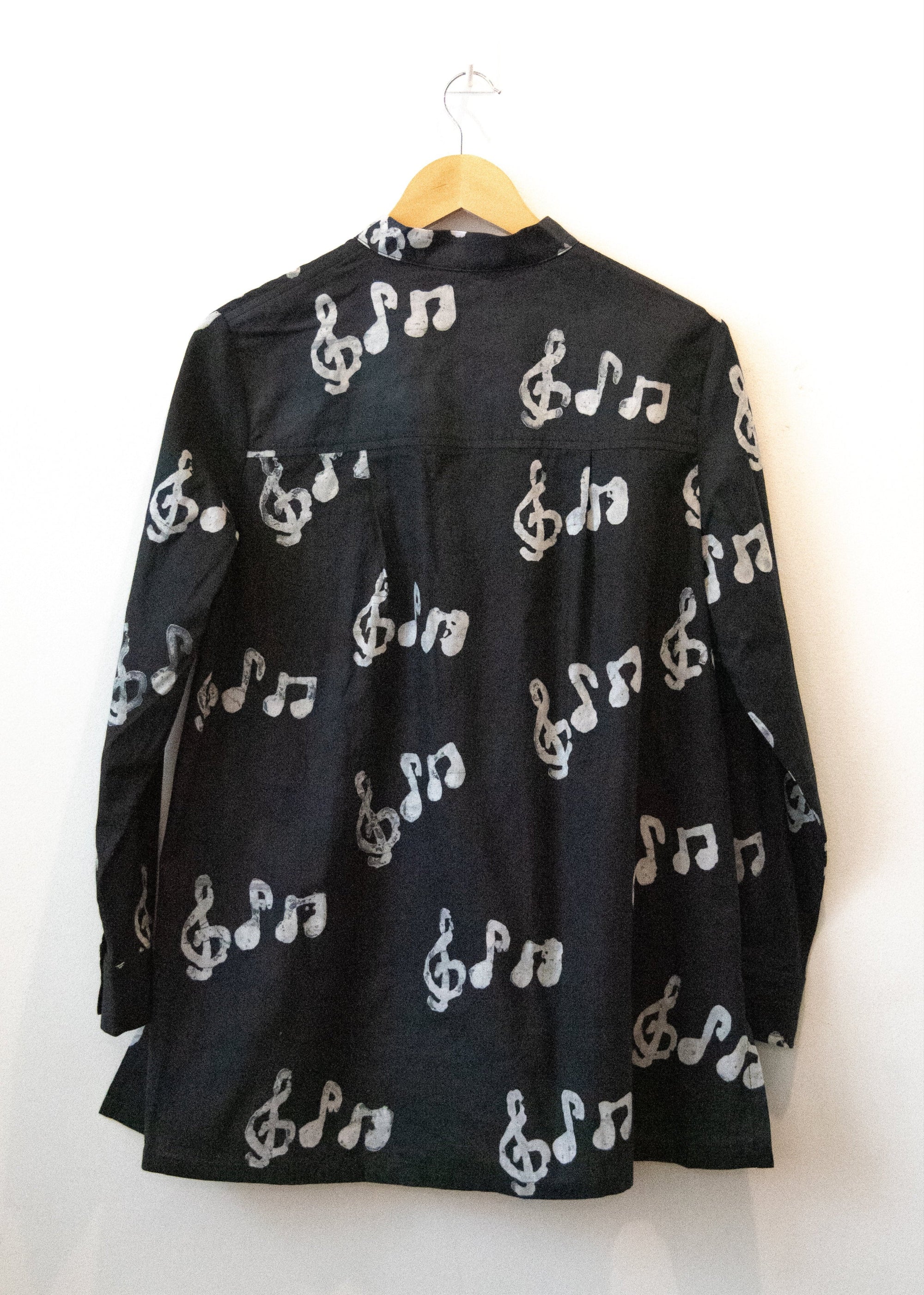 Display of black long sleeved shirt with white music print design.