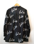 Display of black long sleeved shirt with white music print design.