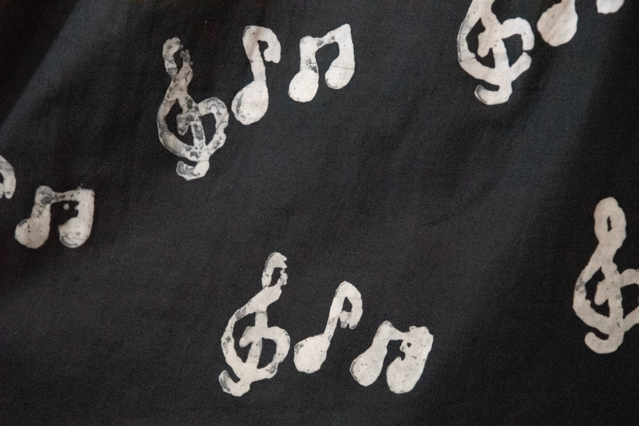 Close up display of black long sleeved shirt with white music print design, fabric.