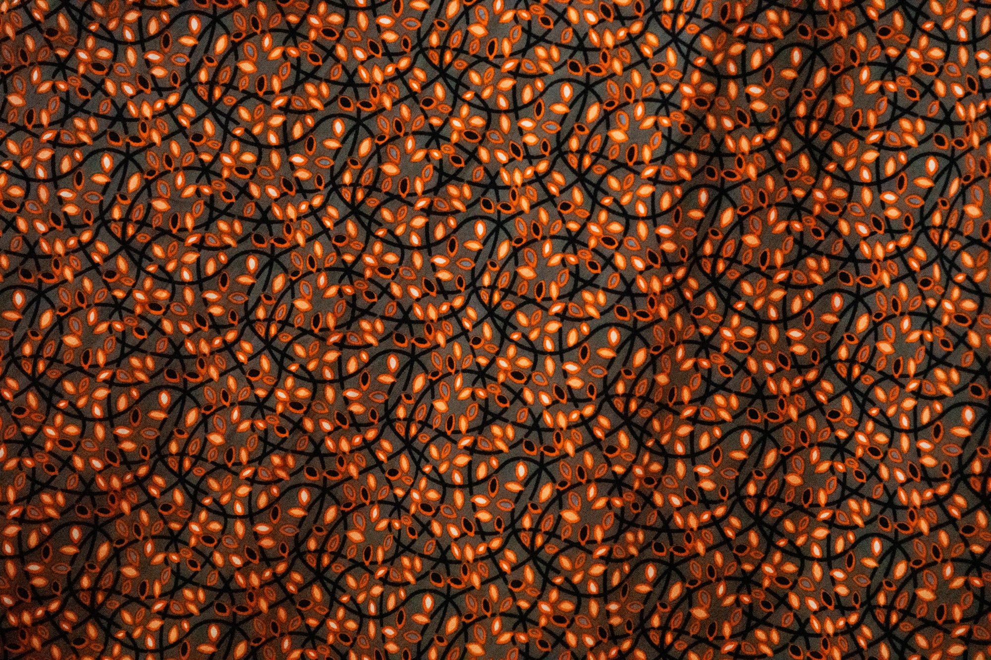 Close up display of grey dress with black and orange vine design, fabric.
