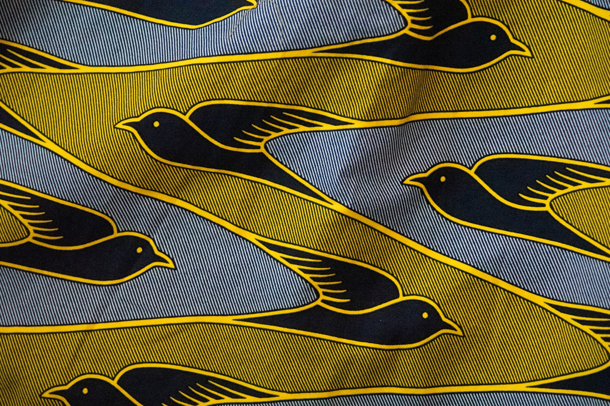 Close up display of yellow, navy and white dove print shirt, fabric.