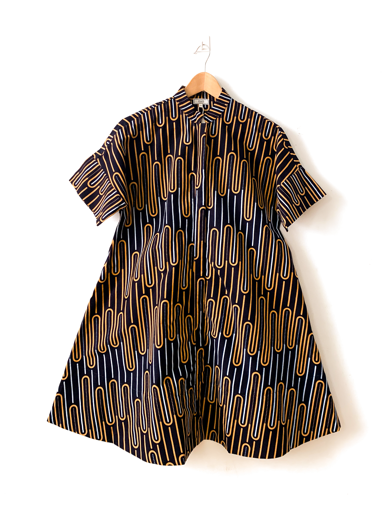 Display of deep navy dress with gold and white geometric line print.