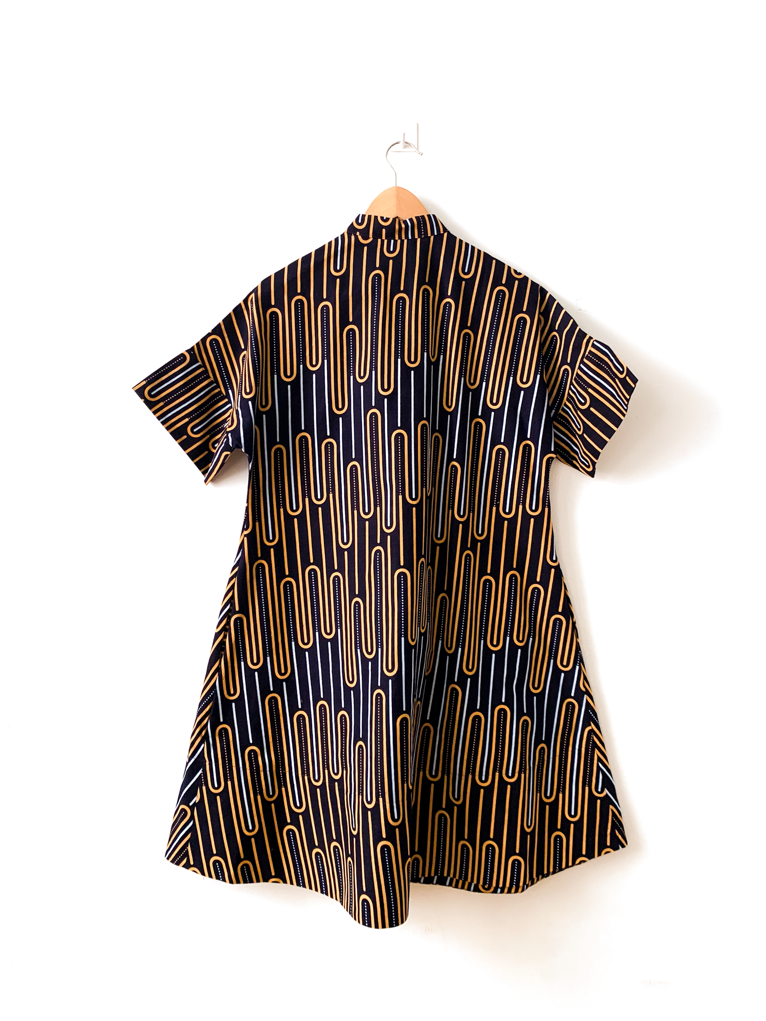 Display of deep navy dress with gold and white geometric line print.