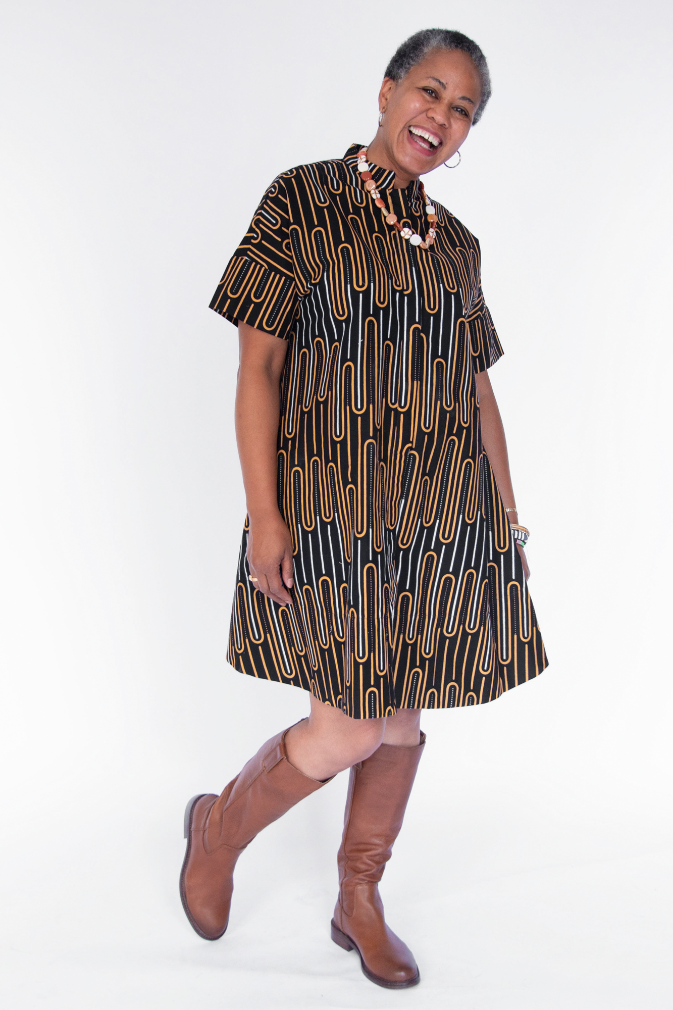 Model wearing deep navy dress with gold and white geometric line print.