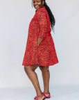 Model wearing red dress with black and white vine print.