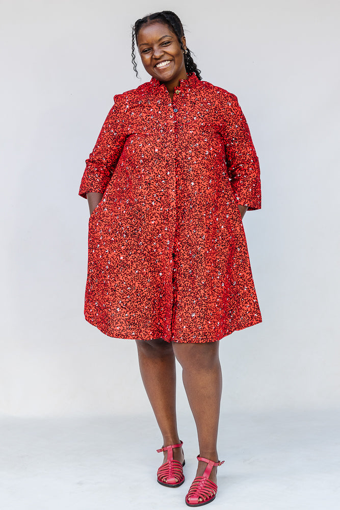 Model wearing red dress with black and white vine print.