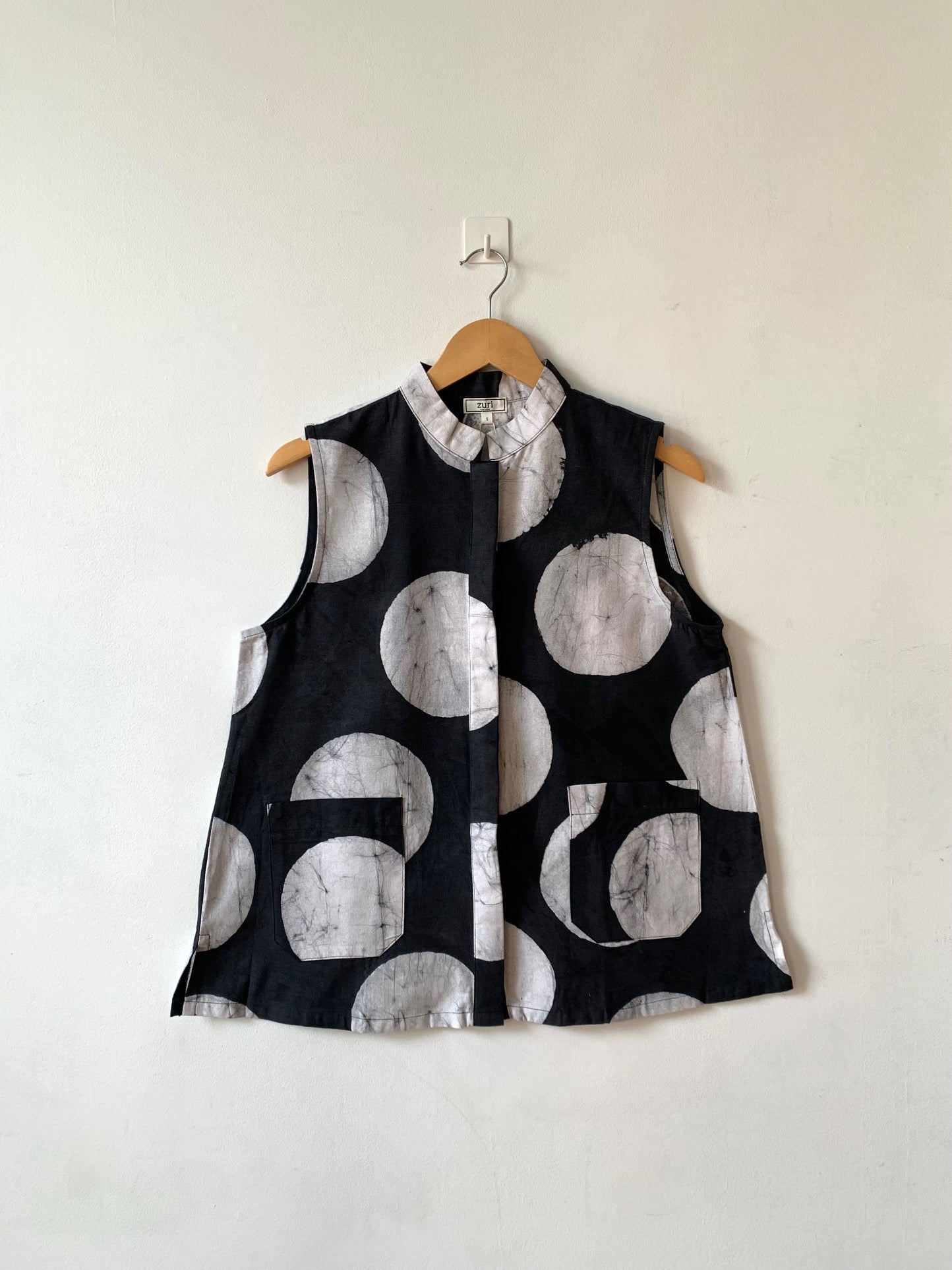 Display of black sleeveless shirt with white circles print.