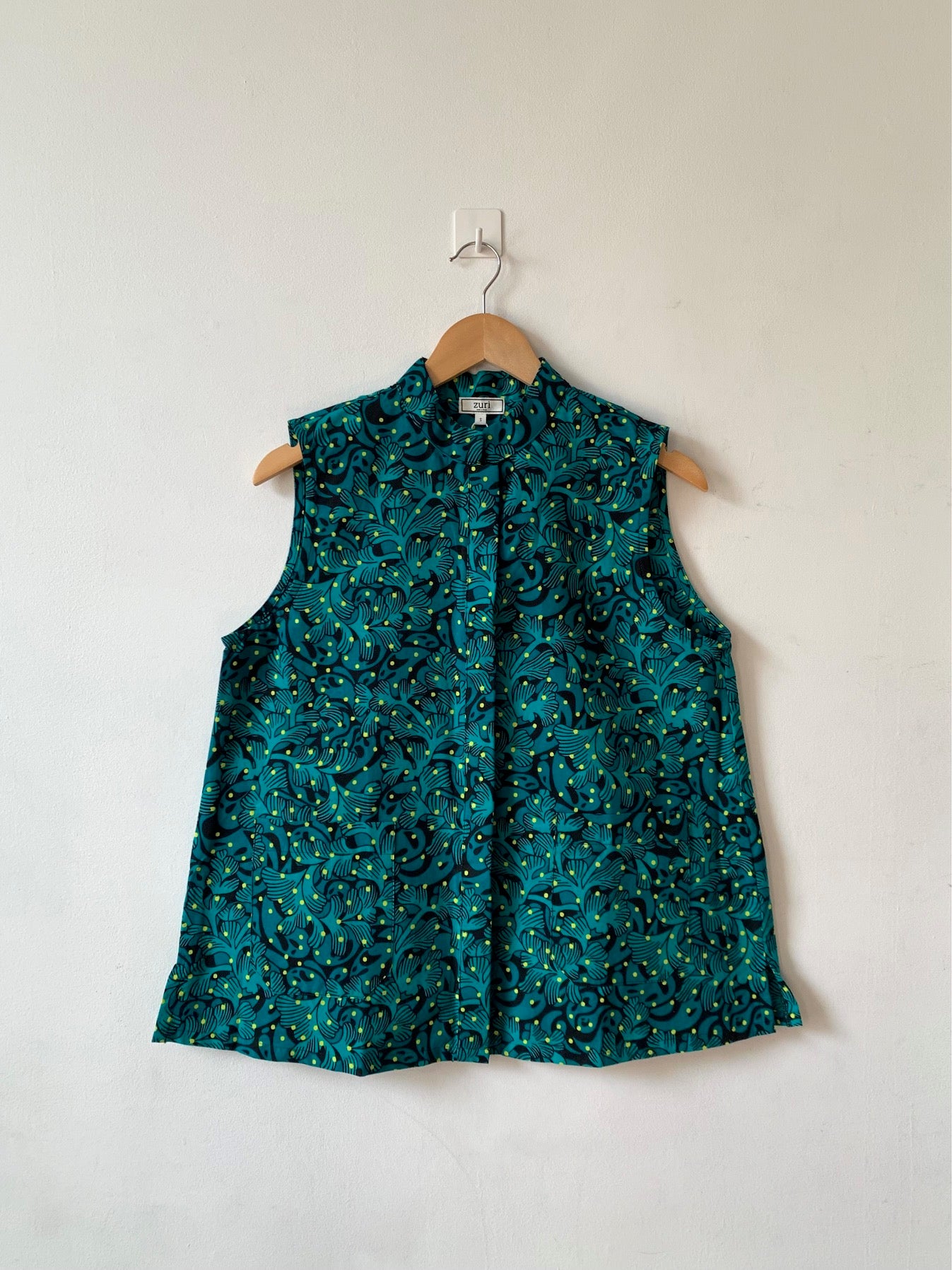 Display of teal, black and yellow floral print sleeveless shirt.