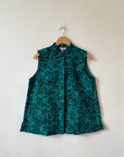 Display of teal, black and yellow floral print sleeveless shirt.