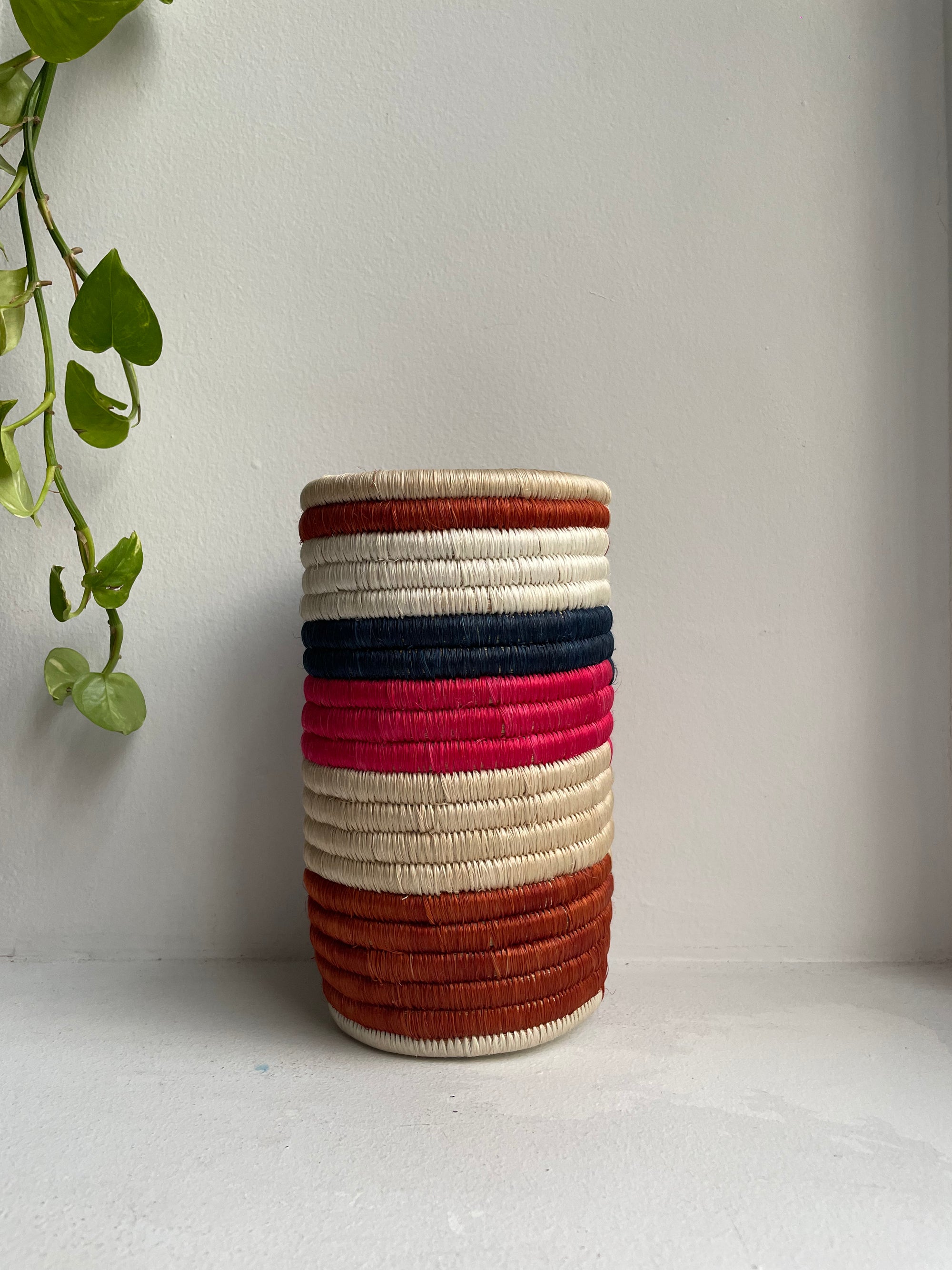 Display of navy, beige, brown and pink striped vase