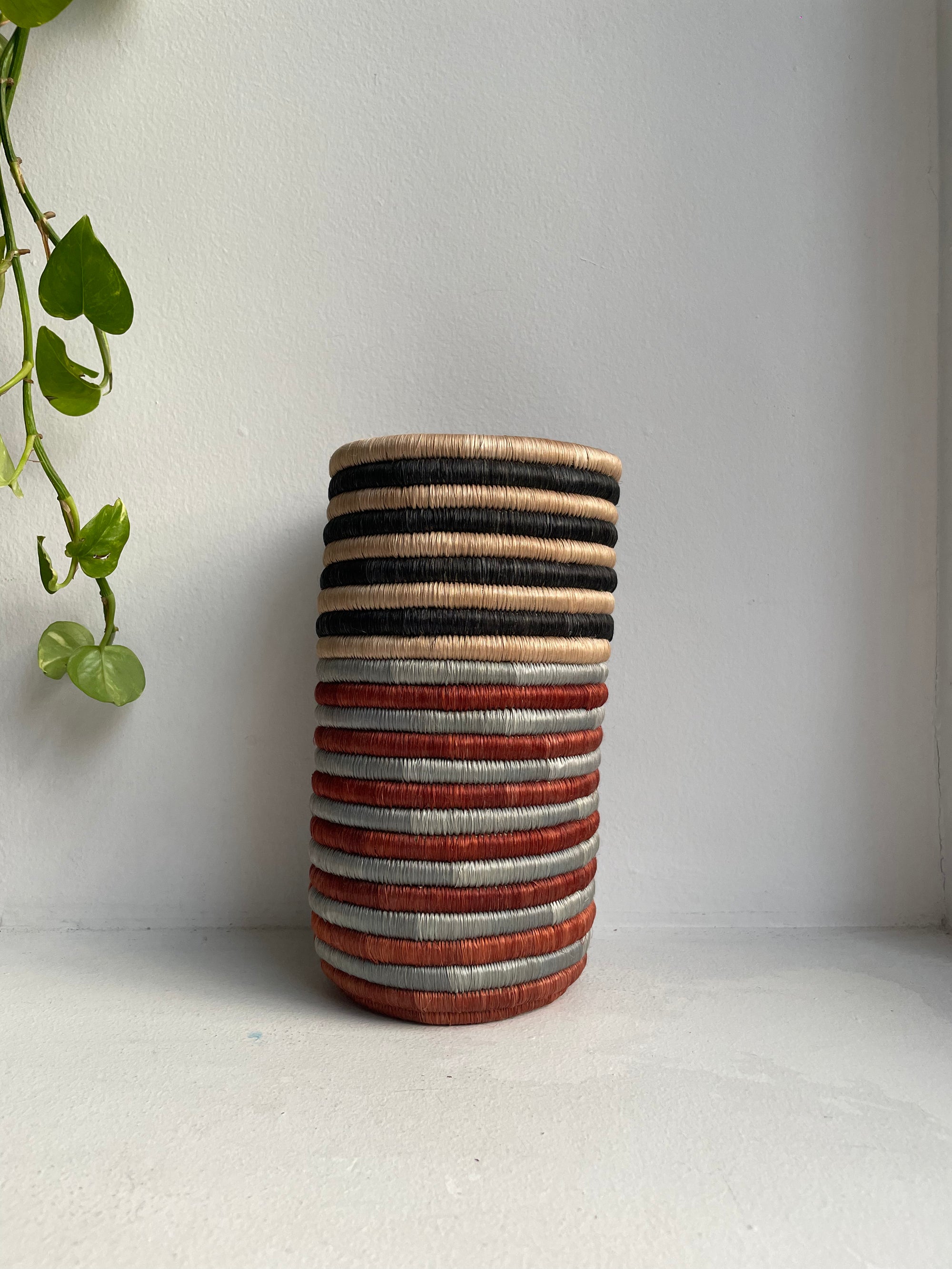 Display of black, beige, grey and brown striped vase
