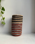 Display of black, beige, grey and brown striped vase