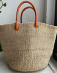 Natural woven sisal basket with leather handle.