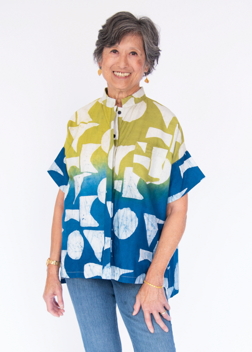 Model wearing yellow, green and blue geometric print batik shirt.