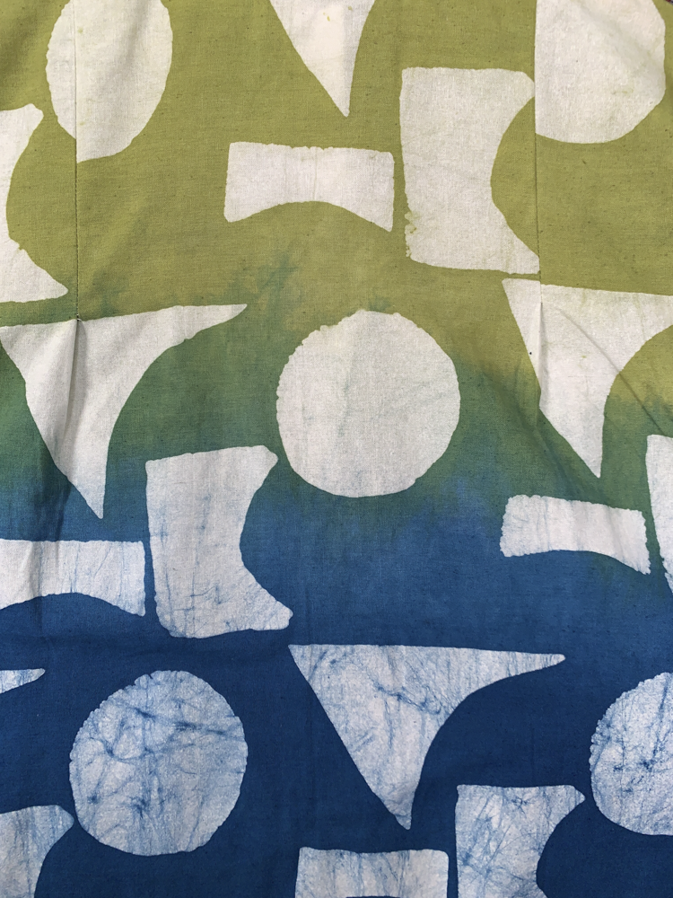 Close up display of yellow, green and blue geometric print batik shirt, fabric.