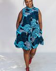 Model wearing sleeveless dress with blue tree print.