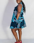 Model wearing sleeveless dress with blue tree print.