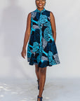 Model wearing sleeveless dress with blue tree print.
