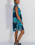 Model wearing sleeveless dress with blue tree print.