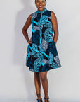 Model wearing sleeveless dress with blue tree print.