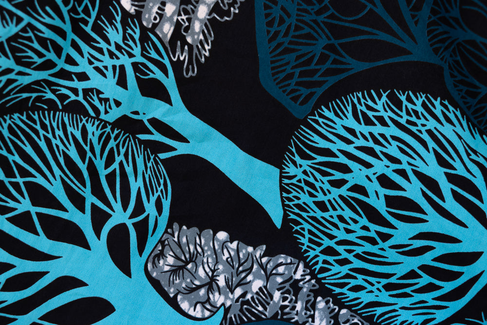 Close up display of sleeveless dress with blue tree print, fabric.