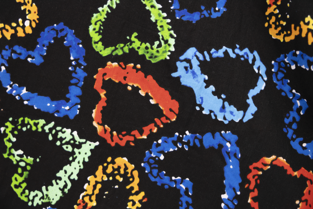 Close up display of black dress with multicolored heart print pattern, fabric.