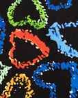 Close up display of black dress with multicolored heart print pattern, fabric.
