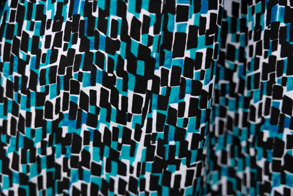Close up display of blue, black and white abstract print sleeveless shirt, fabric.